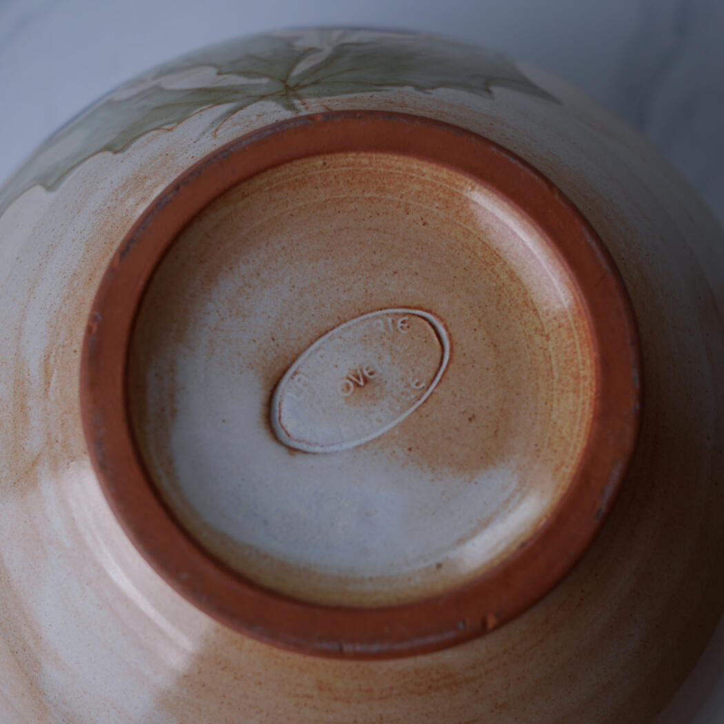 Bottom of a glazed ceramic bowl showing a brown foot ring and an oval maker's mark that reads 'LOVE'.