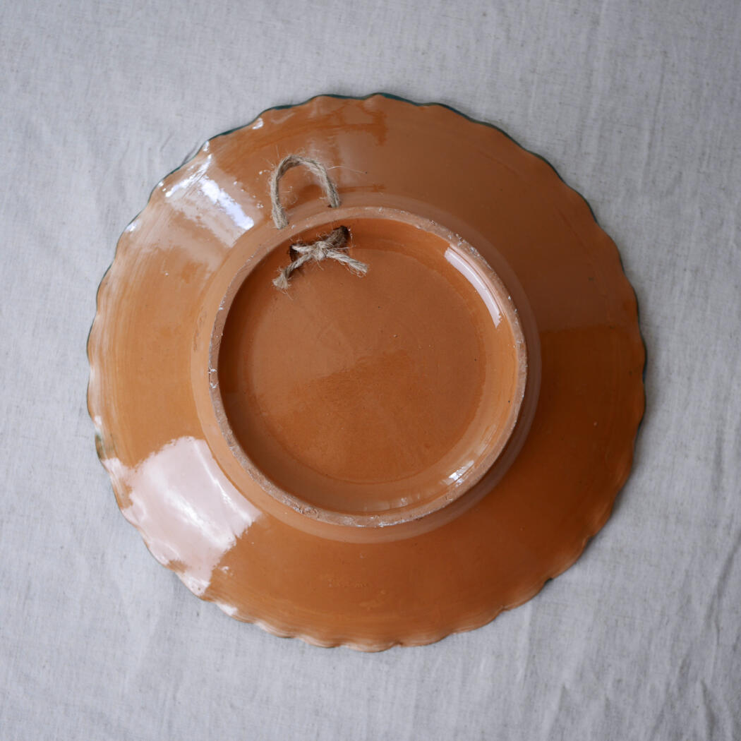 Terracotta plate with scalloped edge, hollow center and a hanging jute string.