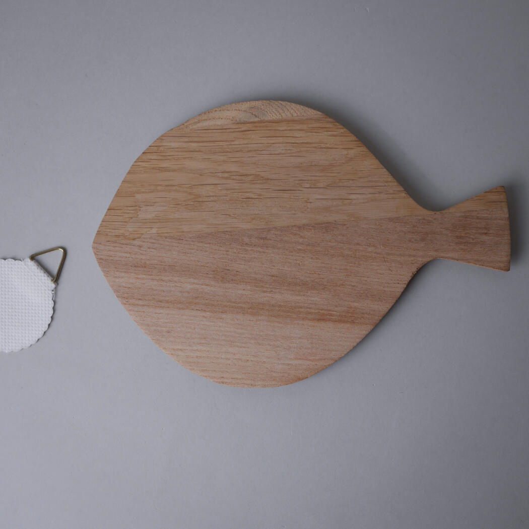 Wooden paddle-shaped cutting board on a gray surface, with a white face mask visible to the left.