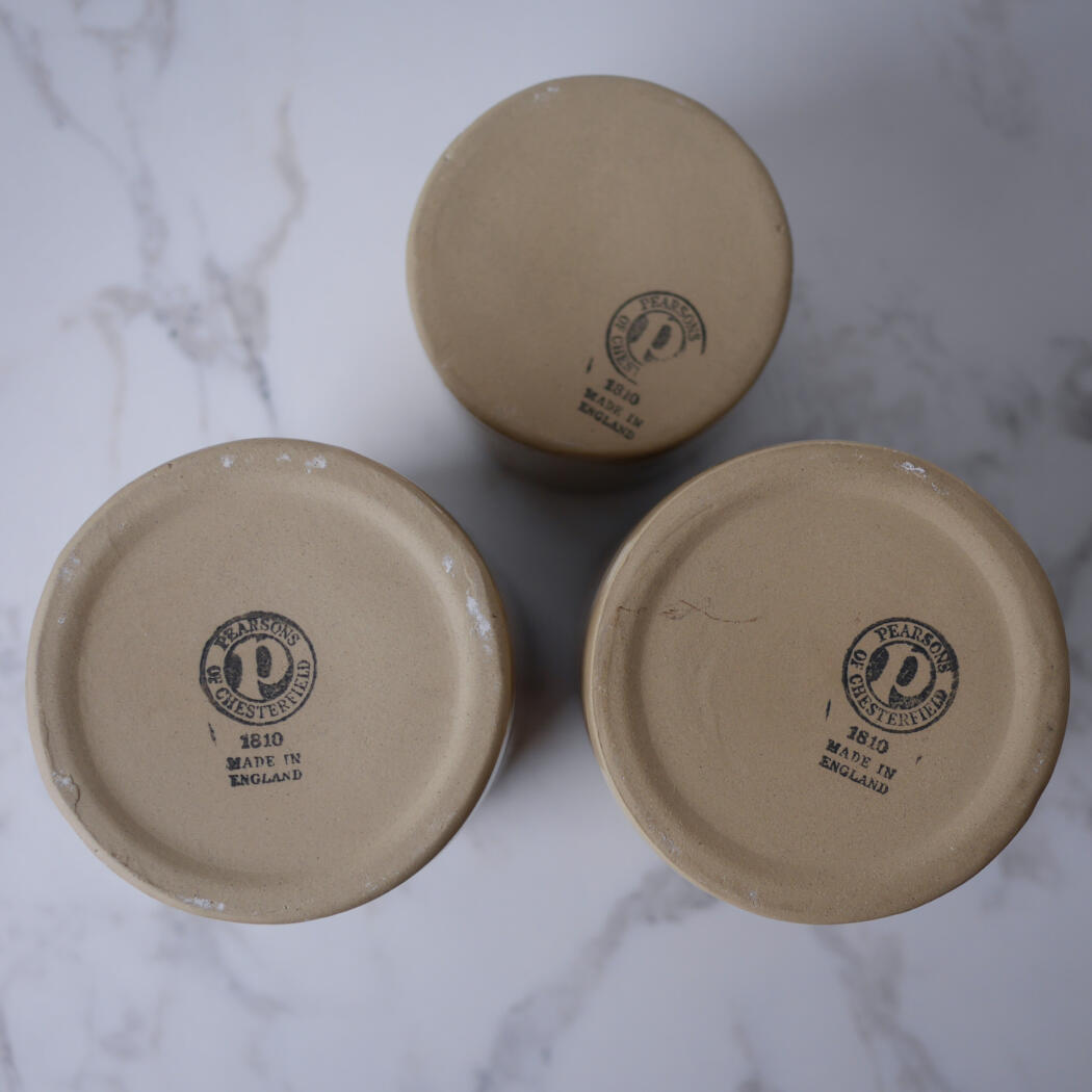 Bottoms of three beige ceramic jars with circular maker's marks reading 'Pearsons of Chesterfield' and '1810 Made in England'