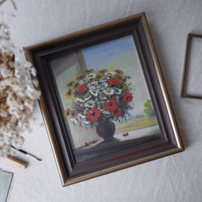 Framed still-life painting of a vase with red poppies and white daisies on a table.
