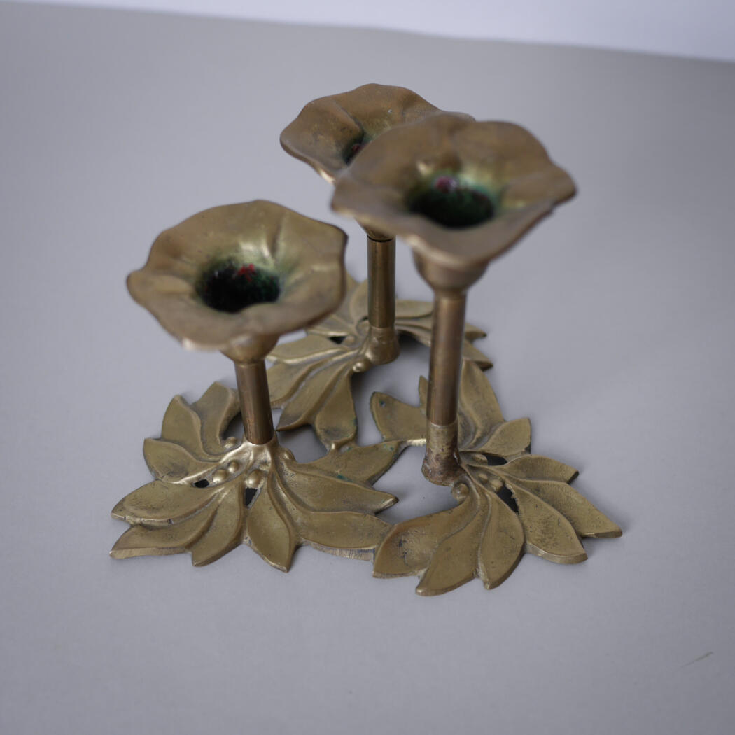 Gold-tone metal candle holder with three open flower cups and a leaf-shaped base, decorative centerpiece.