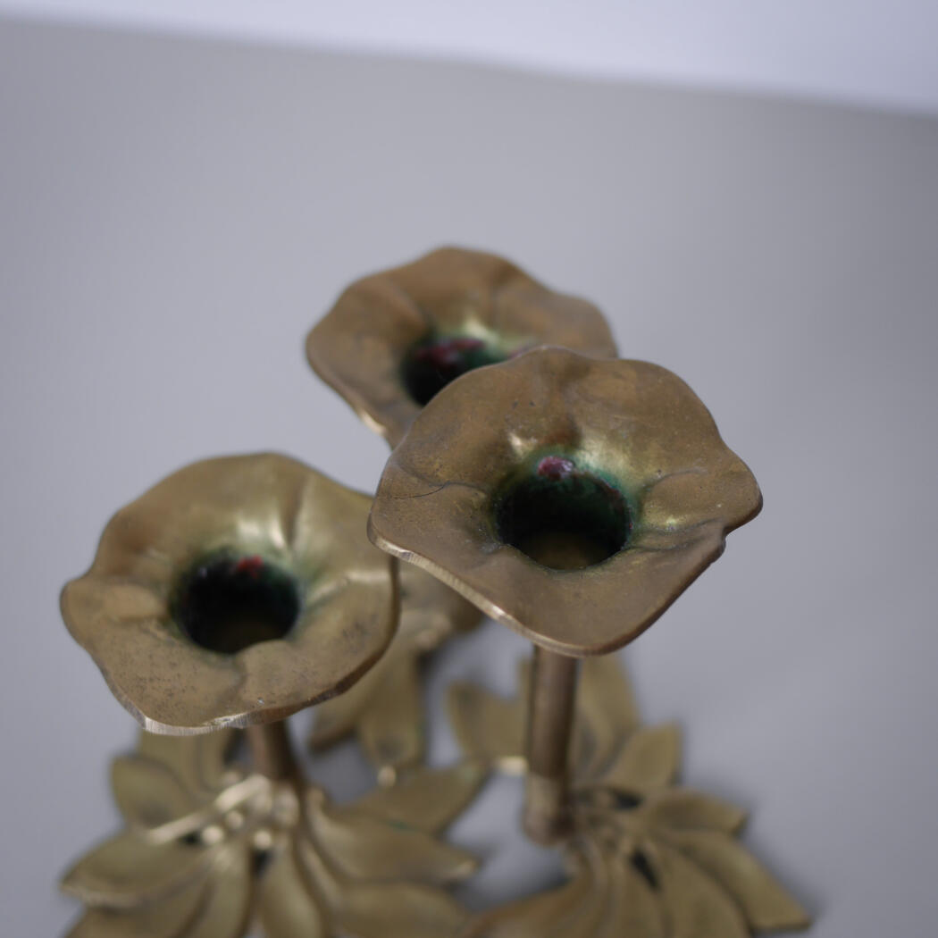 Close-up of gold-tone metal flowers with green centers in a decorative sculpture.