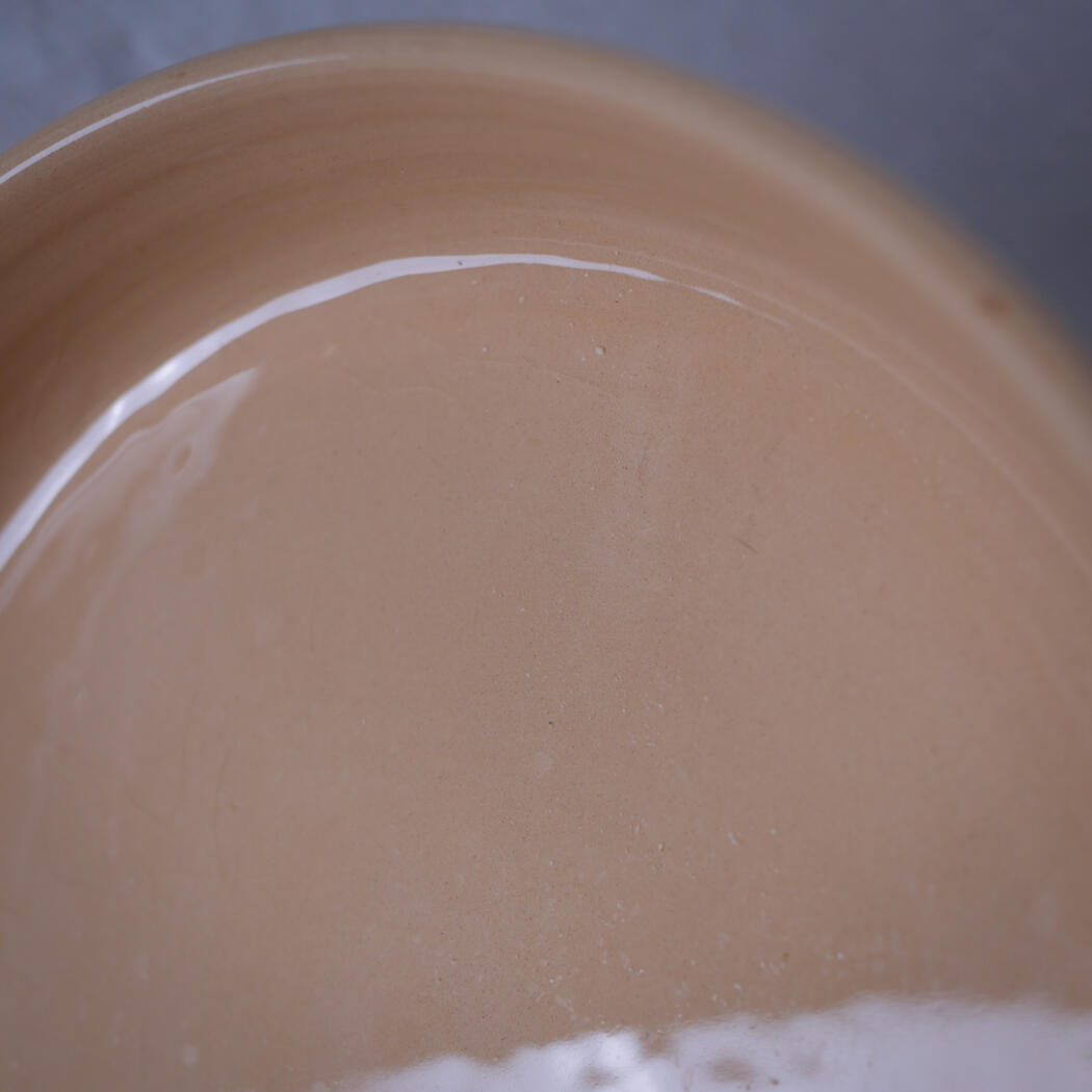 Close-up of a tan ceramic bowl with a white glaze line along the rim.
