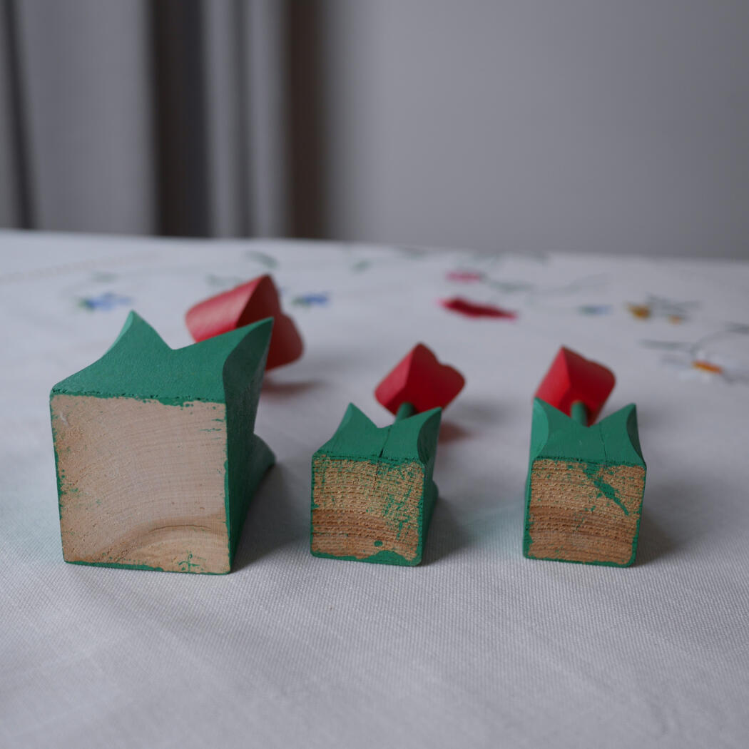 Three wooden blocks painted green with red mountain peaks sit on a white tablecloth.