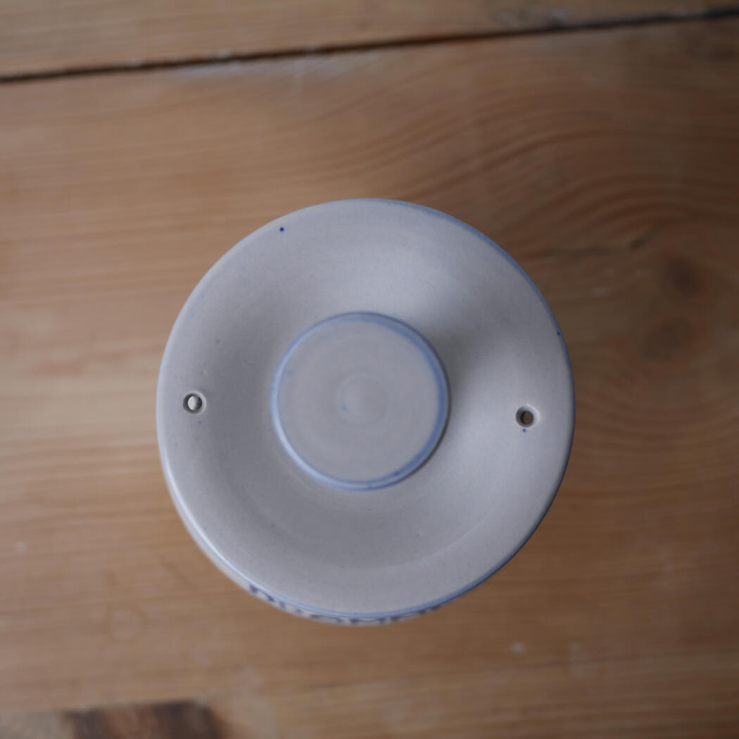 Top-down view of a blue-and-white ceramic jar with a lid on a wooden surface.