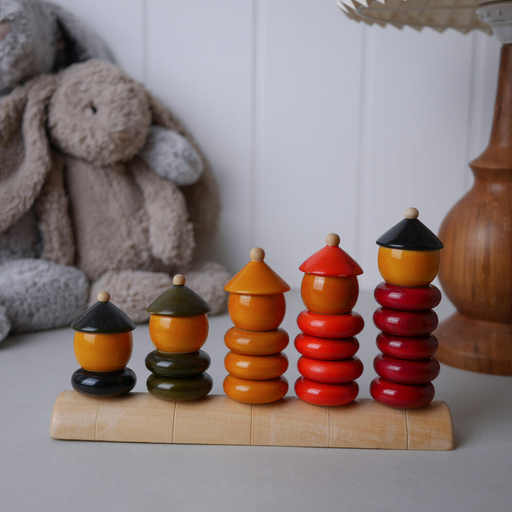 Five colorfully stacked bead towers on a curved wooden base, with plush rabbits in the background.